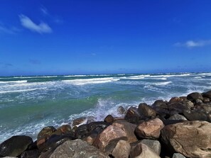 A rocky shoreline with waves crashing against the rocks under a clear blue sky. - 6 Person Holiday Home in Lokken (Lokken)
