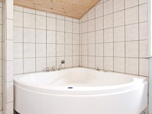 A bathroom with a freestanding bathtub, tiled walls, and a wooden ceiling. - 6 Person Holiday Home in Lokken (Lokken)