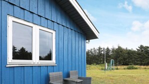A blue building with two large windows and a patio area with wicker furniture. - 6 Person Holiday Home in Lokken (Lokken)
