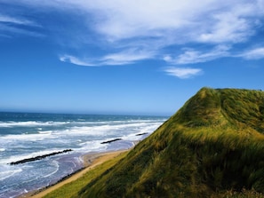 A coastal landscape with a grassy cliff, beach, and ocean waves. - 5 Star Holiday Home in Hjorring (Hjørring)