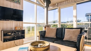 Ett mysigt vardagsrum med en soffa, ett bord med en bok och en dekorativ skål, en tv och en radio.