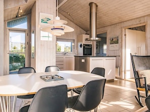 A modern kitchen with a dining area, featuring a large island, stainless steel appliances, and a view of the outdoors. - 5 Star Holiday Home in Hjorring (Hjørring)