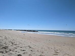 A beach with footprints, waves, and birds.
