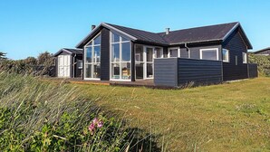Ett modernt hus med stora fönster och ett sluttande tak.