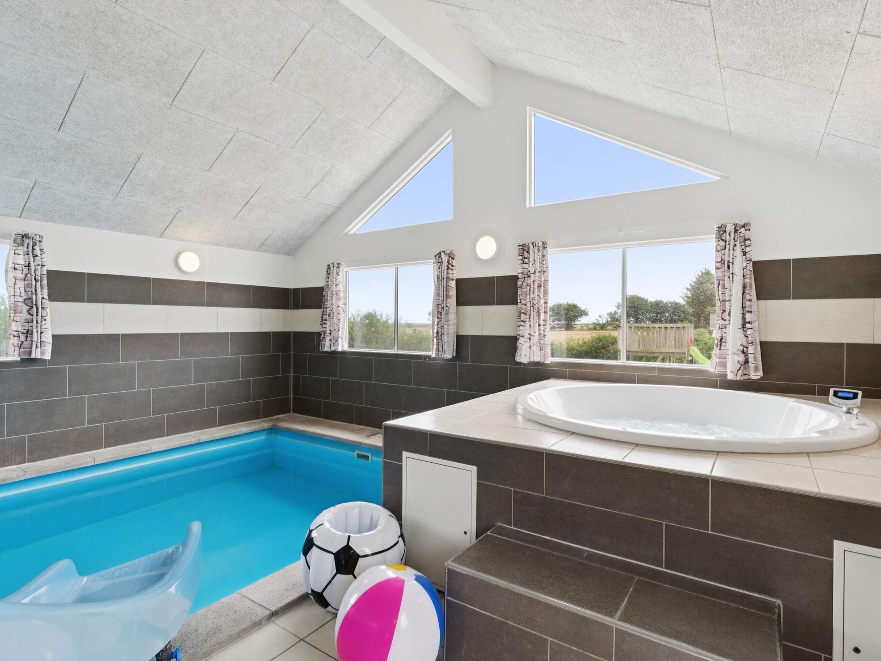 A modern bathroom with a built-in pool, a bathtub, and a shower area.