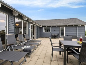 A patio area with outdoor furniture, including chairs and a table, and a building with a tiled roof. - 5 Star Holiday Home in Spottrup (Spøttrup)