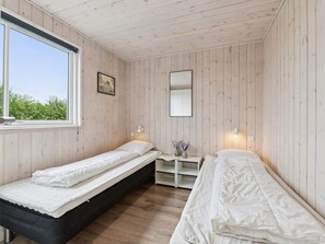 A room with two single beds, a small table with a lamp, a mirror, and a window with a view of greenery. - 5 Star Holiday Home in Spottrup (Spøttrup)