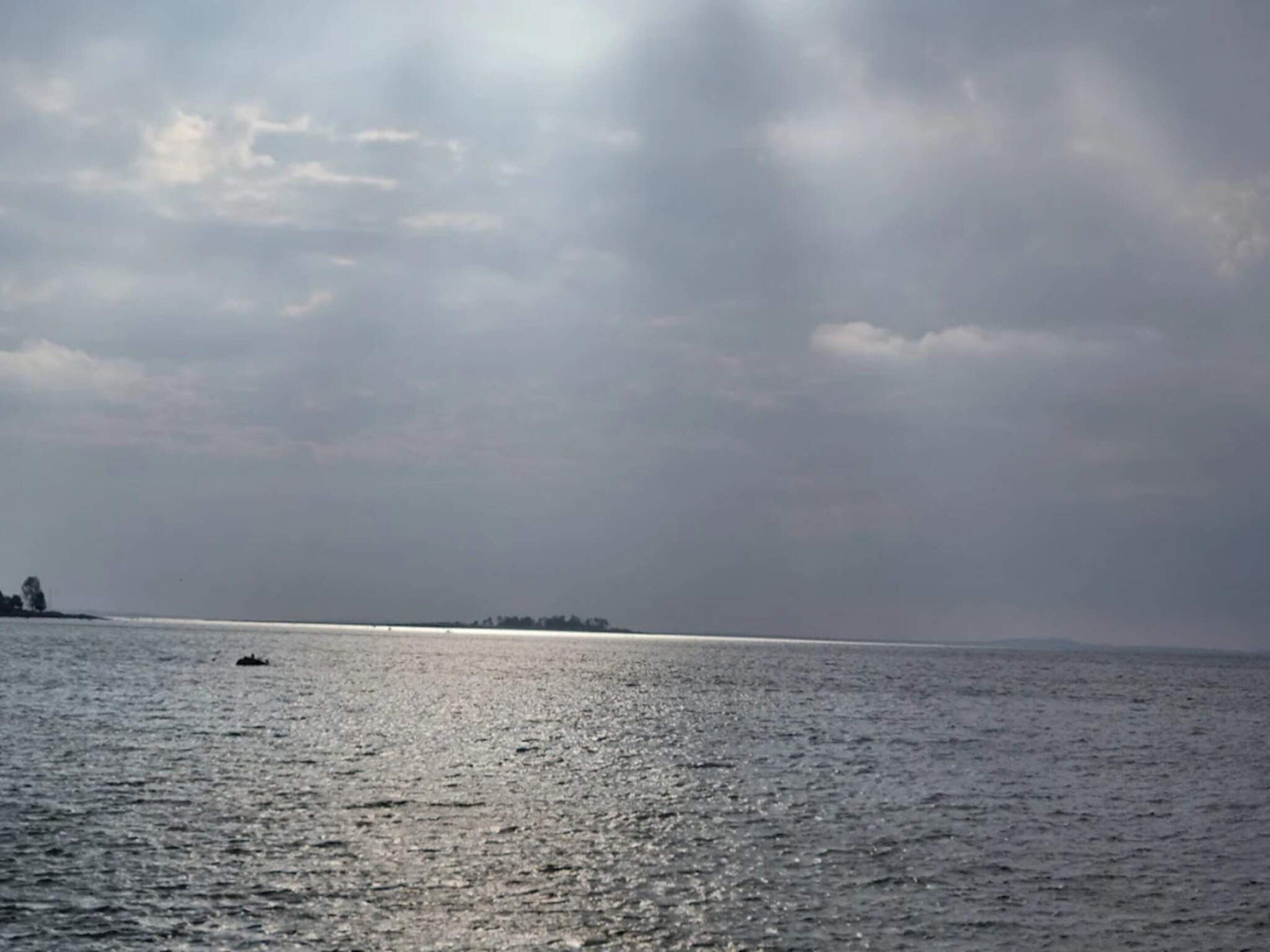 A body of water with a distant shoreline and a boat.