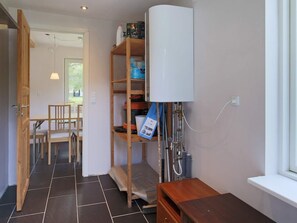 A room with a wooden chair and table, a white cabinet, and a window.