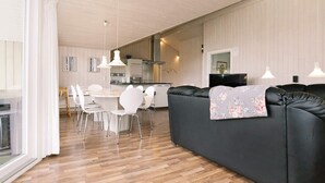 A modern living room with a black sofa, white chairs, and a wooden floor.