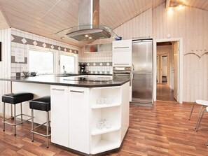 A modern kitchen with a central island, stainless steel appliances, and a wooden floor. - 4 Star Holiday Home in Vaeggerlose (Vaeggerlose)
