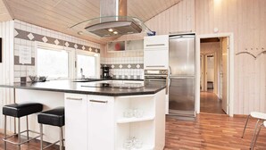 A modern kitchen with a central island, stainless steel appliances, and a herringbone tile backsplash.
