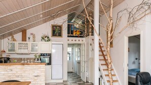 Una cocina amplia con techo alto, una escalera y un comedor con mesa y sillas de madera.