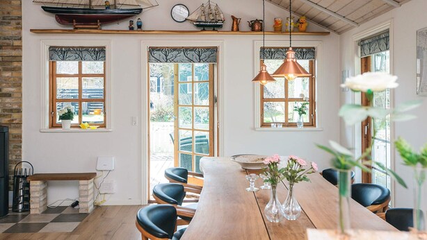 Un comedor con una mesa de madera, sillas e iluminación colgante.
