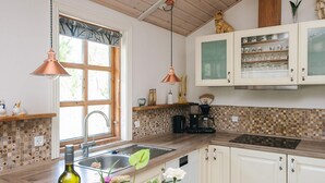 Una cocina con ventana, un lavabo, una cafetera y una botella de vino.