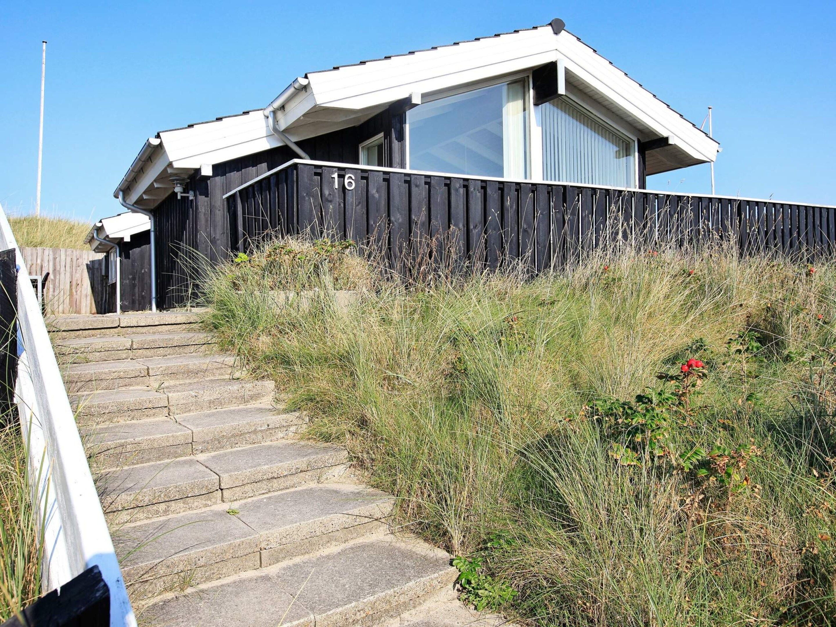 A building with a number 16 sign, a set of stone steps leading up to it, and a surrounding grassy area.