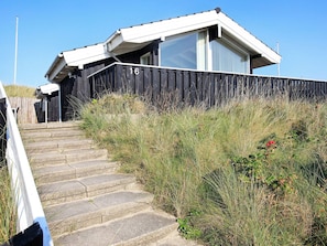 A building with a number 16 sign, a set of stone steps leading up to it, and a surrounding grassy area. - 4 Star Holiday Home in Lokken (Lokken)