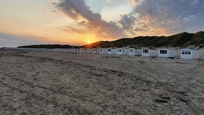 A row of white beach huts with a sunset in the background. - 4 Star Holiday Home in Lokken (Lokken)