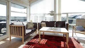 A spacious balcony with a wooden ceiling, a sofa, a table, and a view of the cityscape. - 4 Star Holiday Home in Lokken (Lokken)