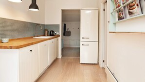 A kitchen with white cabinets, a wooden countertop, a double-door refrigerator, and pendant lights. - 4 Star Holiday Home in Vejby (Vejby)