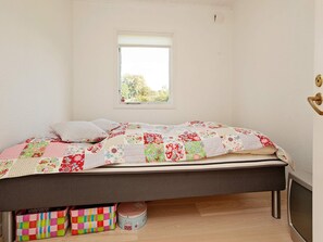 Un dormitorio con cama, ventana, televisor y cajas de almacenamiento debajo de la cama.