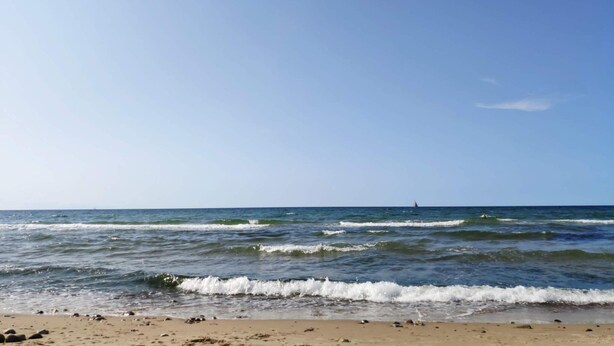 A beach with waves, a clear sky, and a distant sailboat. - 4 Star Holiday Home in Vejby (Vejby)