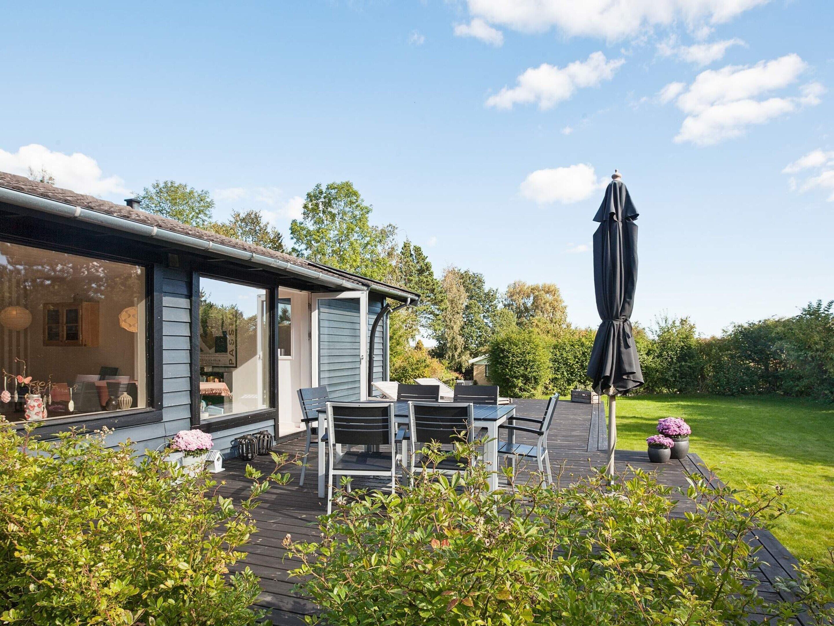 A house with a patio area, outdoor furniture, and a large umbrella.