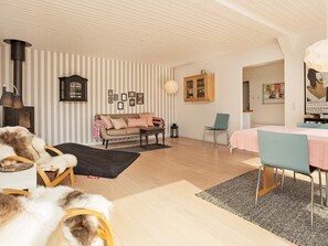 A cozy living room with a sofa, a dining table, and a fireplace. - 4 Star Holiday Home in Vejby (Vejby)
