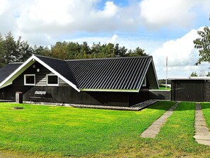 A single-story building with a sloped roof, a bench outside, and a well-maintained lawn. - 4 Star Holiday Home in Ansager (Ansager)