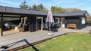 A modern cabin with a covered patio, outdoor seating, and a wooden deck. - 4 Star Holiday Home in Lokken (Lokken)