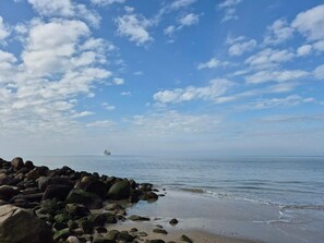 A rocky shoreline with calm water and a distant ship. - 4 Star Holiday Home in Lokken (Lokken)