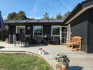 A wooden deck with outdoor furniture, a potted plant, and a small garden area. - 4 Star Holiday Home in Lokken (Lokken)