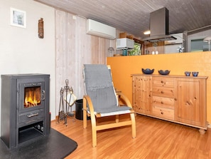 A cozy room with a wood-burning stove, a wooden chair, a cabinet, and a window.