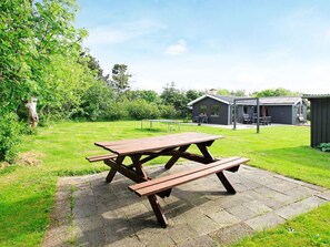 A picnic table in a grassy area with a building in the background. - 4 Star Holiday Home in Lokken (Lokken)
