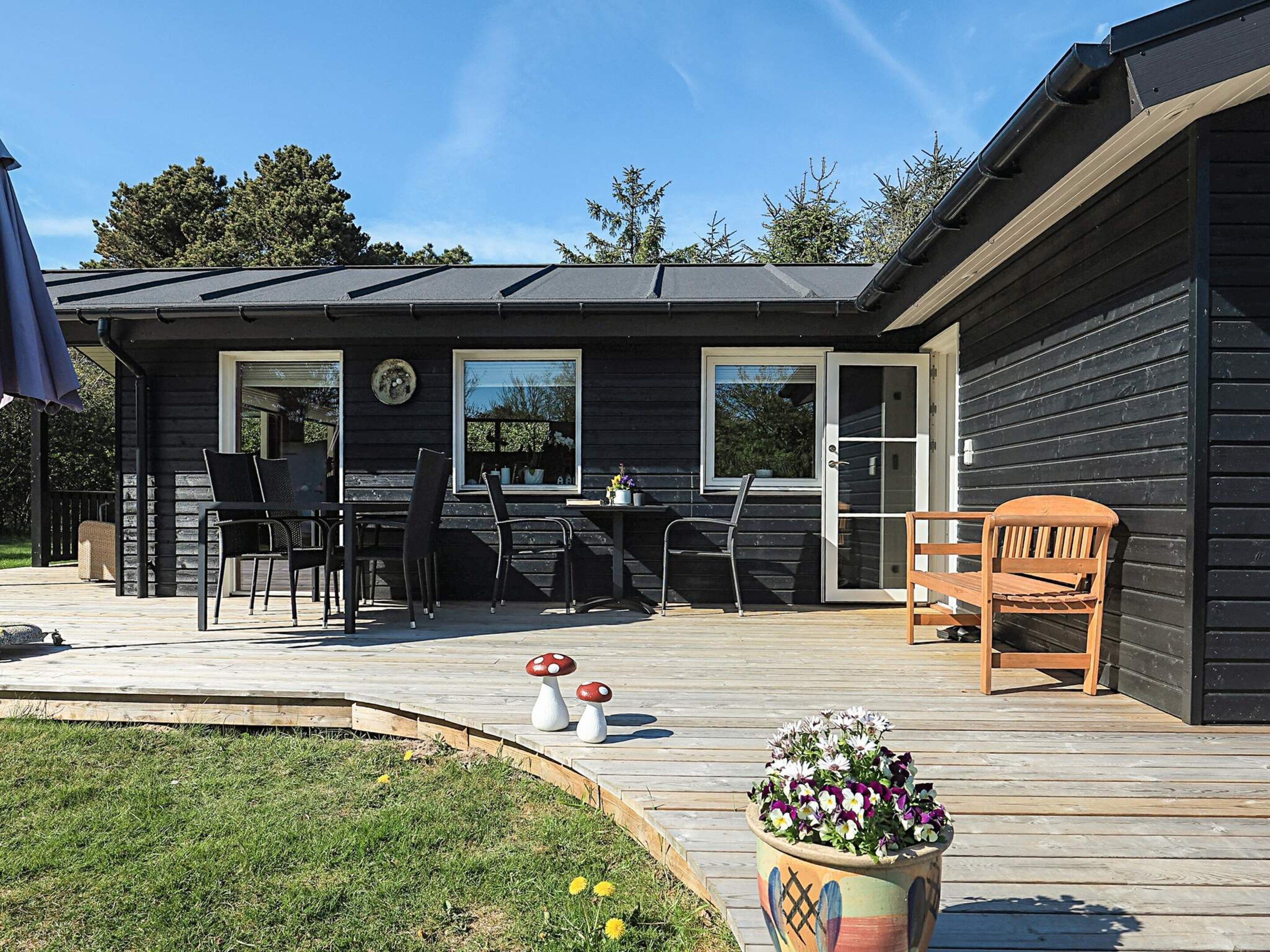 A wooden deck with outdoor furniture, a potted plant, and a small garden area.