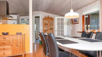 A dining area with a white table, black chairs, and a hanging light fixture.