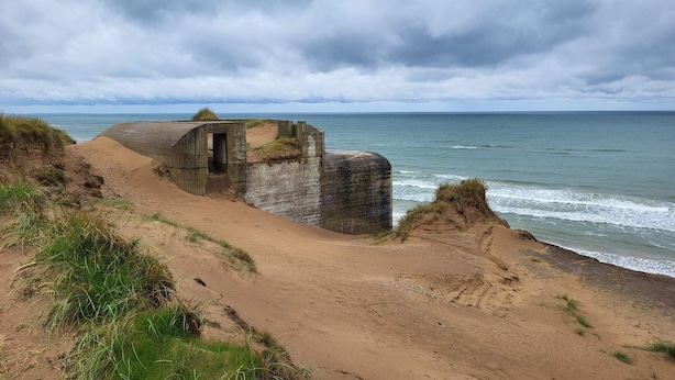 A coastal landscape with a sandy beach, a stone structure, and the ocean under a cloudy sky. - 4 Star Holiday Home in Lokken (Lokken)