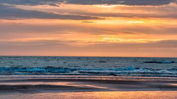 A beach with waves and a sunset.