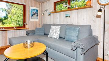 A cozy room with a grey sofa, a small round table, and a lamp.