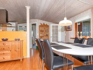 A dining area with a white table, black chairs, and a hanging light fixture. - 4 Star Holiday Home in Lokken (Lokken)