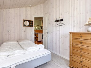 A bedroom with a bed, a wooden dresser, and a wall-mounted coat rack. - 4 Star Holiday Home in Lokken (Lokken)