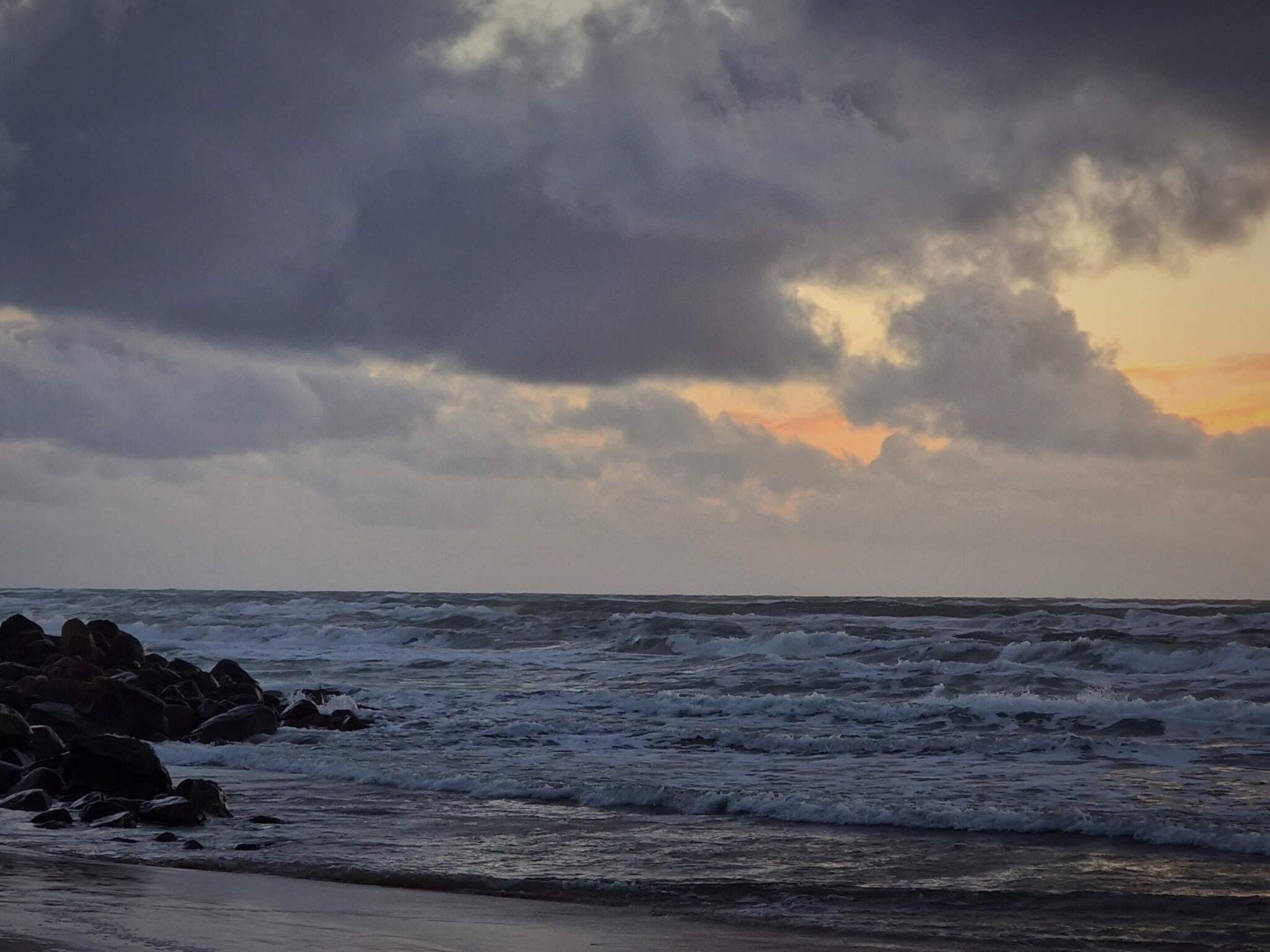 A beach with waves and rocks.