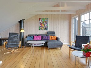 A modern living room with a sectional sofa, two armchairs, a coffee table, and a large window providing natural light.
