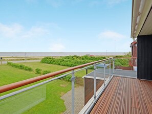A balcony with a view of the sea and a grassy area.