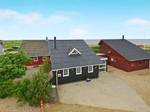 A rural setting with a black house featuring a gabled roof and a red barn. - Tasteful Holiday Home in Hemmet near Sea (Hemmet)