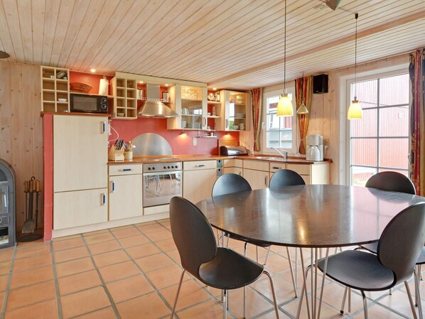 A kitchen with a dining table and chairs, wooden cabinets, and a stove.