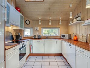 A modern kitchen with wooden cabinets, a built-in oven, a coffee machine, and a microwave.