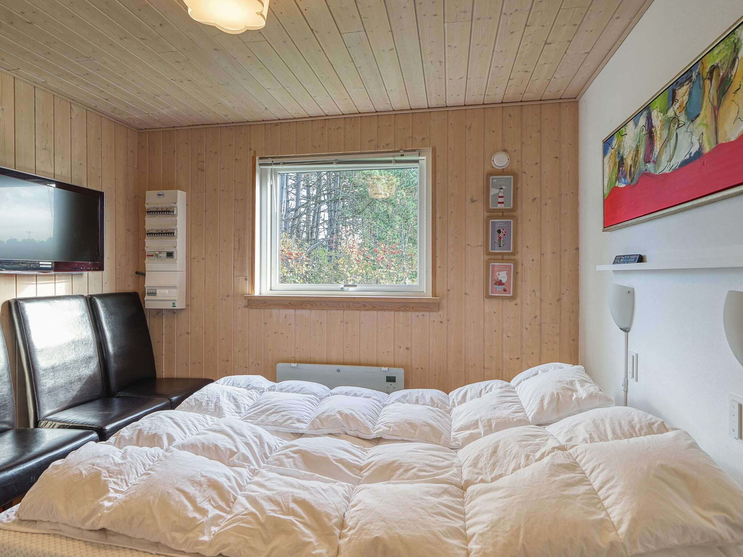 Ein Schlafzimmer mit einem Bett, einem Fernseher, einem Fenster und einem Gemälde.