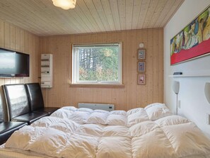 A bedroom with a bed, a TV, a window, and a painting. - 5 Star Holiday Home in Rodby (Rodby)
