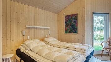 Ein Zimmer mit einem Bett, einem Sessel, einem Gemälde und einer Tür, die nach draußen führt.